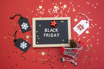 Black Friday Sale Board with Mini Shopping Cart, Star Confetti, and Festive Sale Tags on Red Background