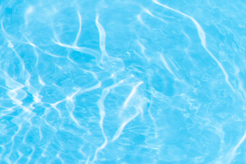 Blue water with ripples on the surface. Defocus blurred transparent blue colored clear calm water surface texture with splashes and bubbles. Water waves with shining pattern texture background.