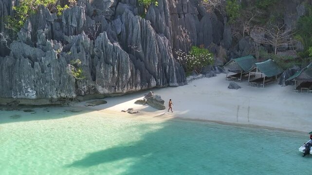 Aerial view of a beautiful tropical beach with a woman walking along the shore, Coron, Palawan, Philippines.