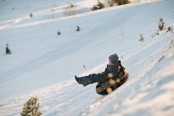 A child rides a tubing in winter from a hill