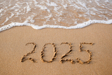 The inscription 2025 on the sand by the sea. Happy New Year.