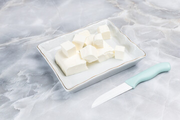 Sliced feta - white cheese in the saucer. Top view.