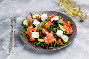 Salad with salmon, white cheese and vegetables on the plate with ingredients.