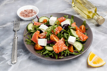 Salad with salmon, white cheese and vegetables on the plate with ingredients.