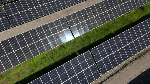 Aerial angled dolly over Solar Farm in Finland showcasing bifacial panels and clean energy with gravel and grass between panels