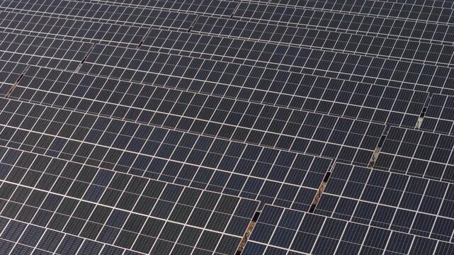 Drone angled bird's eye orbit of sun beam glistening on bifacial solar panels producing renewable energy
