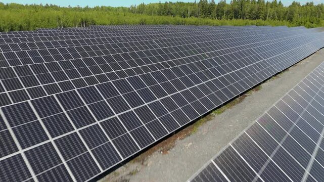 Low aerial tracking pullback fast over bifacial solar panels at Solar Farm in Finland, energy production with gravel between rows
