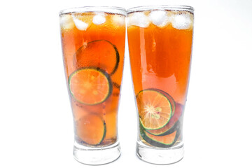 Close up Glass of iced tea with lemon, lime and ice cubes isolated on white background. Two glasses of sweet iced tea filled with lemon slices