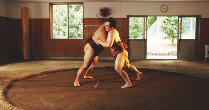 Combat, fighting or Sumo wrestling with men in dohyo for Japanese competition, culture or tournament. Exercise, fitness or training with wrestler and rival in ring of arena for exhibition match