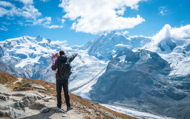 Traveling family enjoying the mountain scenery with a glacier in Switzerland. Dad and baby.