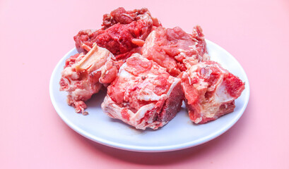 sliced ​​bones and fresh raw beef on a white plate isolated on a pink background. fresh spare ribs