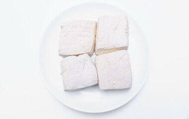 Fresh white tofu cubes on a white plate isolated white background. Fresh soybean tofu.