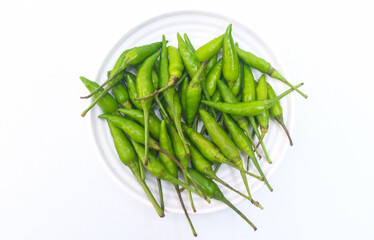 Collection of small green bird's eye chilies on a white plate isolated on a white background. Small hot bird's eye chilies for making chili sauce