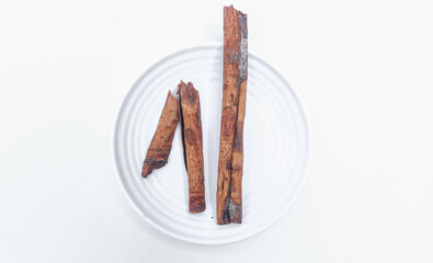 cinnamon stick spice isolated on white background closeup. Cinnamomum verum pieces in a plate