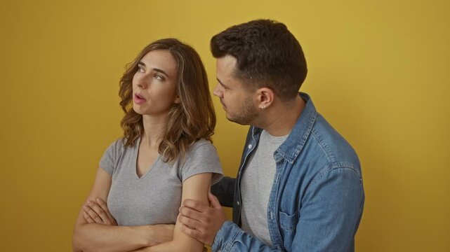 Man and woman in argument over isolated yellow background showcasing relationship tension with expressive body language