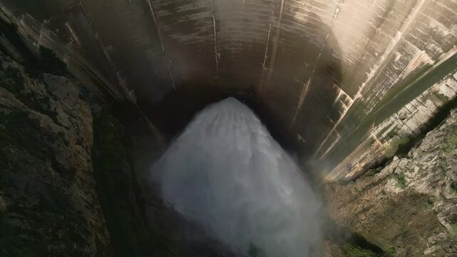 Water discharge from a dam inside a mountain canyon. Pressurized water coming out of the dam. Howell Bunger valve in operation. Aerial overhead view.
