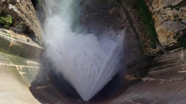 Water discharge from a dam inside a mountain canyon. Pressurized water coming out of the dam. Howell Bunger valve in operation. Aerial overhead view.
