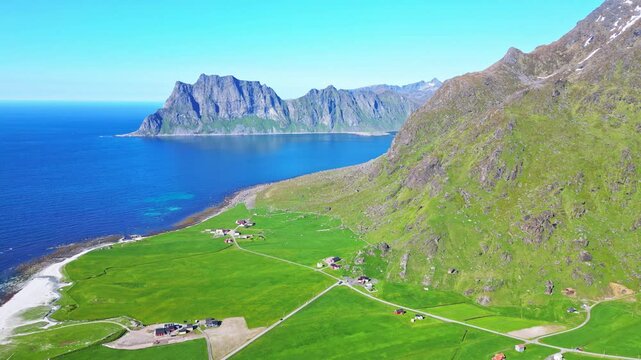 Aerial view of Haukland beach with beautiful coastline, majestic mountains, and green farmland, Leknes, Norway.