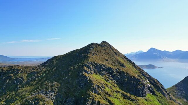 Aerial view of the majestic mountain summit overlooking the tranquil beach and rugged coastline, Uttakleiv, Lofoten, Norway.