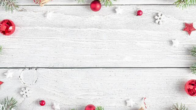 Christmas frame made of snowy fir branches, gift boxes, red decorations and pine cones on white wooden background. Flat lay. Happy New Year and winter holidays background. Top view