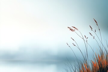 Tranquil morning by the lake with soft mist and delicate grasses swaying in the breeze