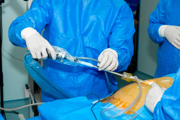 The surgeon's hands hold a surgical manipulator for minimally invasive surgery.