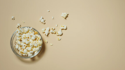 Popcorn in a glass bowl scattered on a light background