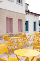 Bright yellow outdoor furniture against textured wall with pink shutters