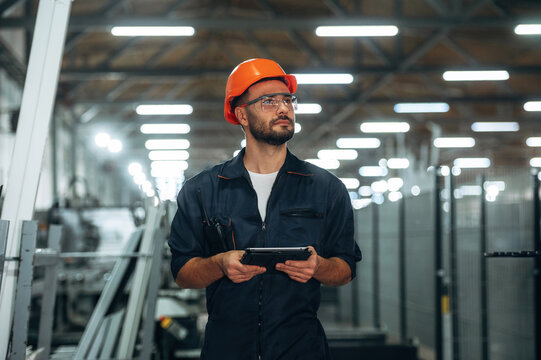 Black colored tablet in hands. Man is working in the modern factory
