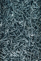 Bunch of galvanized stainless screws with flat countersunk head, hardware background