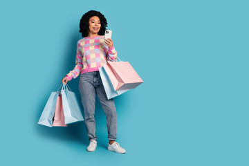 Full size photo of pretty young girl hold shopping bags device wear trendy pink plaid outfit isolated on blue color background