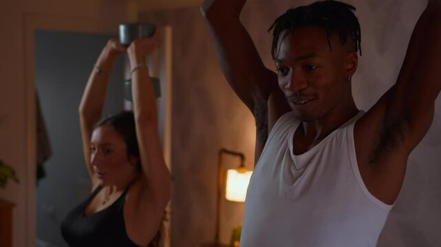 Young Black Man exercising with his girlfriend at home weight training