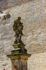 medieval sculpture stands against a stone wall