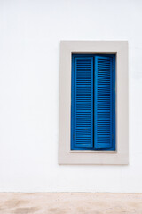 Blue shutters on a textured stone wall in a quiet coastal village