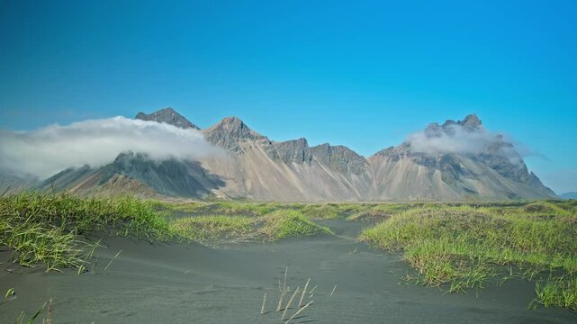 Timelapse of tall scree mountains made of granophyre rocks. Headland with a dramatic mountainscape and black sands.