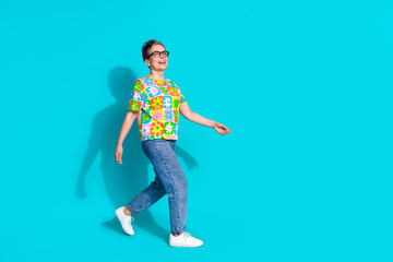 Full size photo of nice aged woman walk empty space ad isolated on teal color background