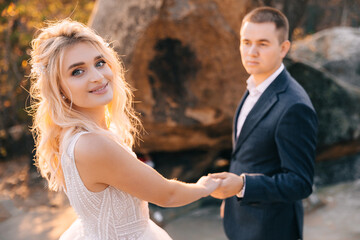 Beautiful newlyweds couple hugging in mountains at sunset. Bride and groom walking in summer Carpathians.