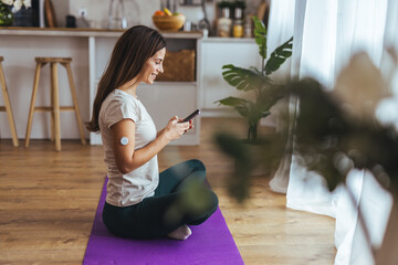 Woman Smiling While Using Smartphone During Indoor Yoga Session