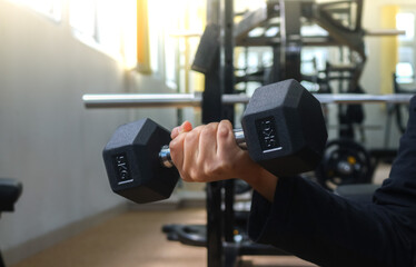 Close up of hands lifting 5 kilo gram dumbbells to train arm and shoulder muscles on the gym hall background. 5 kilogram dumbbell gym equipment with sunlight, work out, lose weight