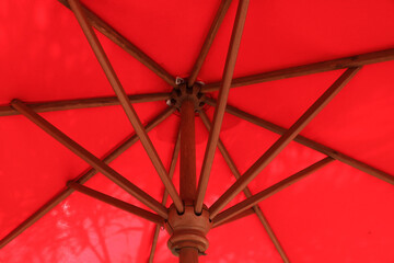 Close up of big red umbrella at the edge of the swimming pool. Large Umbrella Framework