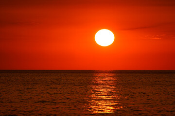 Orange red sunset. Impressive view of a clear sky and sunlight reflecting on the sea.
