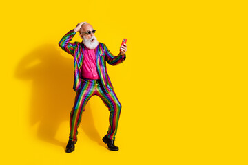 Full body portrait of eccentric man use phone empty space ad wear shiny costume isolated on yellow color background
