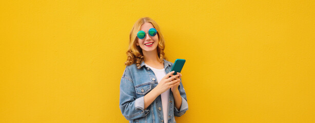 Happy young woman with phone, modern smiling girl holding smartphone in casual denim clothing