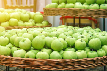 rustic bowl filled with fresh green apples on display outdoors, surrounded by lush green leaves. depiction of organic produce and a healthy lifestyle. harvest demonstration holiday festival