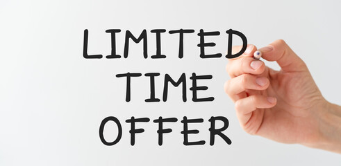 The hand of a business woman with a pen in her hands writes on a transparent background Limited Time Offer, Business Concept.