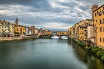 Fototapeta premium Ponte Vecchio medieval bridge above the Arno River in the downtown of Florence, Italy with a cloudy sky above