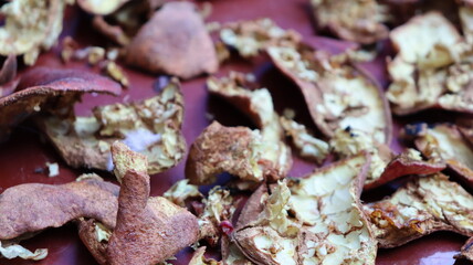 Close-up of dried pomegranate peels scattered on a red surface, highlighting texture and natural detail for eco-friendly, culinary, and sustainable themes
