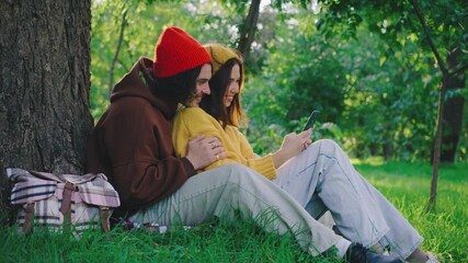 Cozy Moments in Nature A Happy Couple Enjoying Cherished Time Together Under the Canopy of a Tree in a Beautiful Park, Embracing Each Other in a Joyful and Relaxed Atmosphere