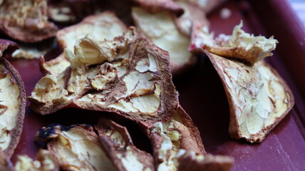 Close-up of dried pomegranate peels scattered on a red surface, highlighting texture and natural detail for eco-friendly, culinary, and sustainable themes
