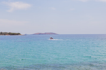 Naklejka premium Motorboat Cruising Across Calm Blue Sea With Distant Islands On The Horizon